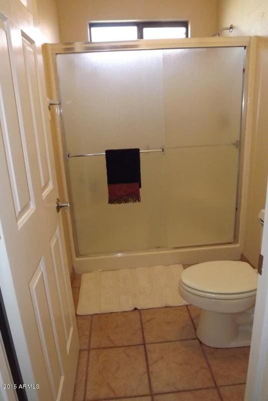 full bathroom featuring tile patterned flooring, a stall shower, and toilet