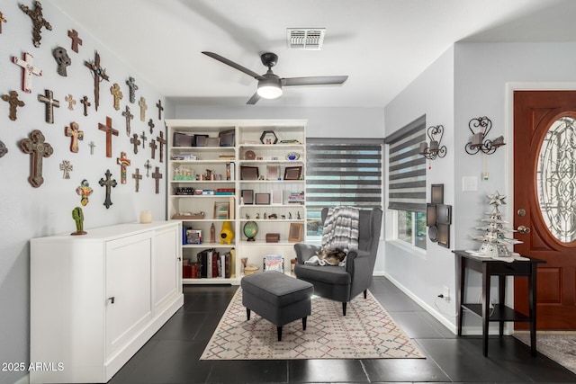 living area featuring baseboards, dark tile patterned flooring, visible vents, and a ceiling fan