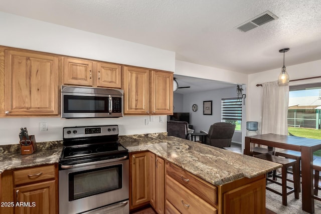 kitchen featuring stainless steel appliances, brown cabinetry, and visible vents