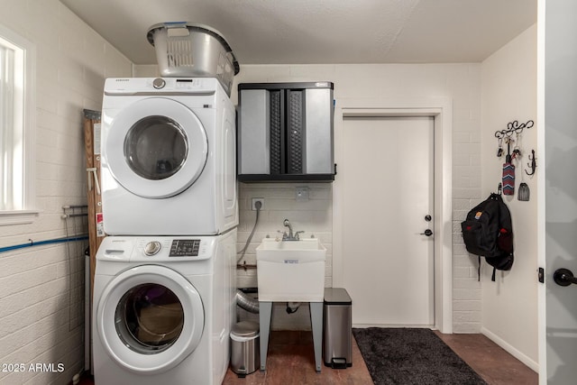 laundry room with stacked washer and dryer, a sink, and laundry area