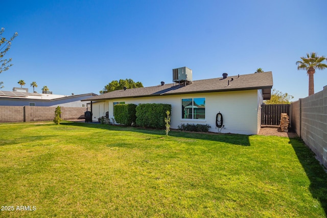 rear view of property featuring a yard, a fenced backyard, and central air condition unit