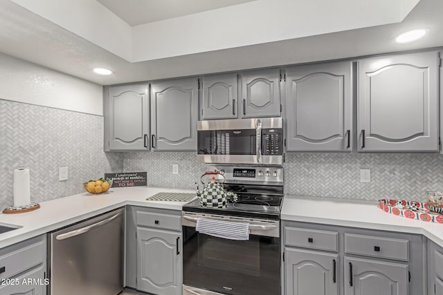 kitchen featuring backsplash, gray cabinetry, light countertops, stainless steel appliances, and recessed lighting