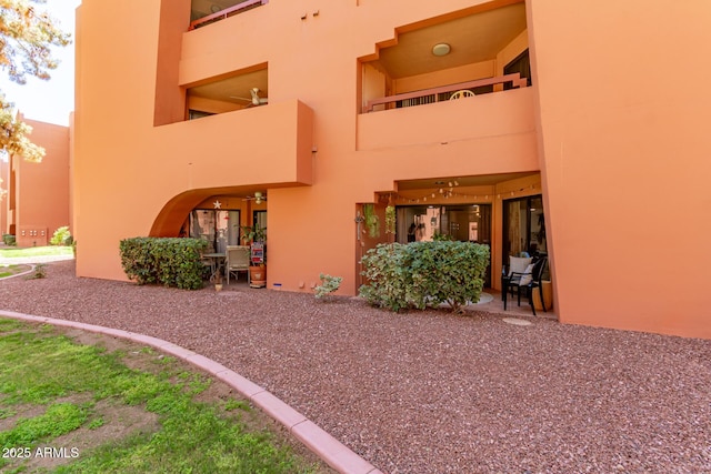 back of house featuring a balcony, a patio area, and stucco siding