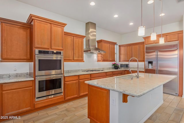 kitchen featuring pendant lighting, sink, wall chimney exhaust hood, an island with sink, and appliances with stainless steel finishes