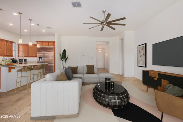 living room featuring ceiling fan, sink, and light hardwood / wood-style flooring