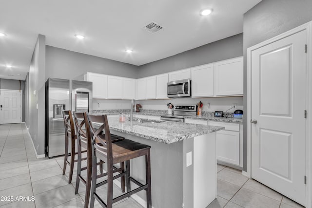 6085 E Athena Rd, Florence, AZ 85132 - kitchen with appliances with stainless steel finishes, light tile patterned flooring, a kitchen island with sink, white cabinetry, and recessed lighting