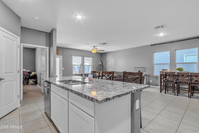 6085 E Athena Rd, Florence, AZ 85132 - kitchen with light tile patterned floors, a ceiling fan, white cabinetry, light stone counters, and a center island with sink