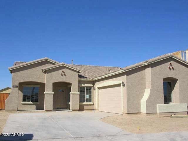 mediterranean / spanish-style house with a tile roof, a garage, driveway, and stucco siding