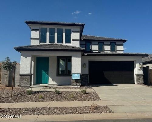 prairie-style house featuring concrete driveway, a garage, and stucco siding