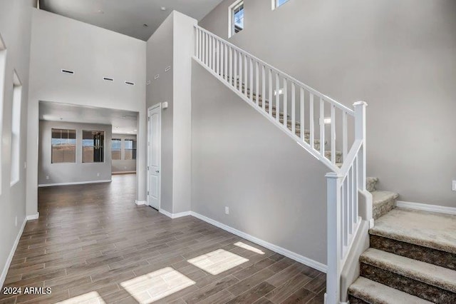 stairs featuring hardwood / wood-style floors and a towering ceiling