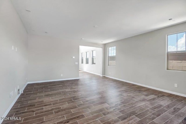 spare room with a wealth of natural light and dark wood-type flooring