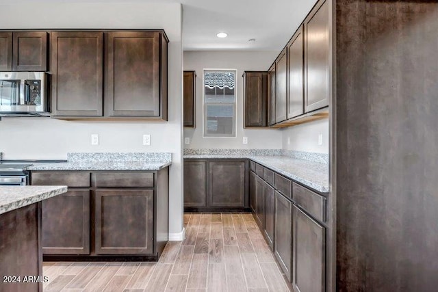 kitchen featuring light stone countertops, dark brown cabinets, and light hardwood / wood-style floors