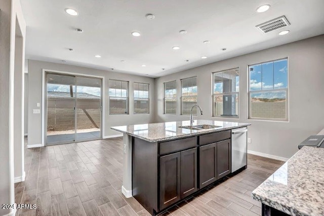 kitchen featuring light stone countertops, sink, stainless steel dishwasher, and light wood-type flooring