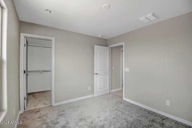 unfurnished bedroom featuring light carpet and a closet