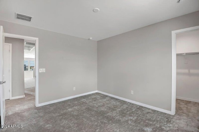 unfurnished bedroom featuring carpet, a walk in closet, and a closet