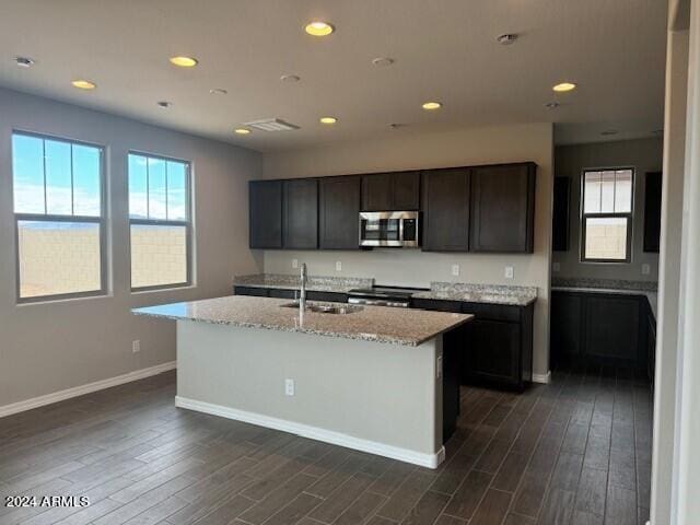 kitchen with dark hardwood / wood-style flooring, stainless steel appliances, a kitchen island with sink, and sink