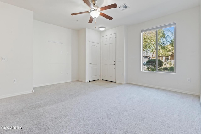 empty room with a ceiling fan, light carpet, visible vents, and baseboards