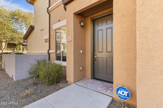 property entrance featuring fence and stucco siding