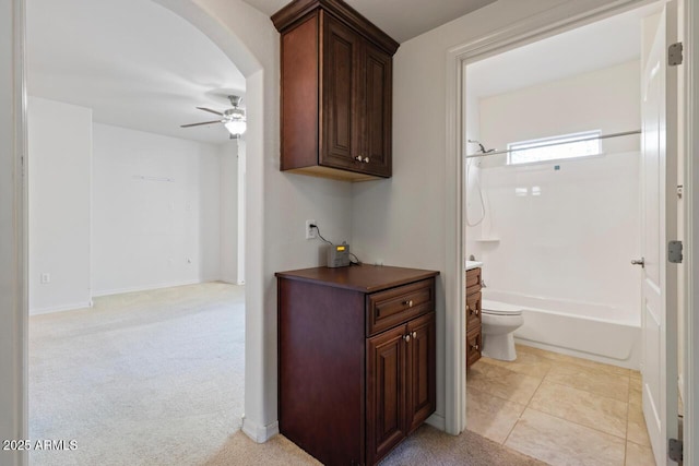 hall with light tile patterned floors, baseboards, arched walkways, and light colored carpet