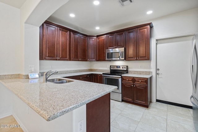 kitchen featuring light stone counters, visible vents, appliances with stainless steel finishes, a sink, and a peninsula