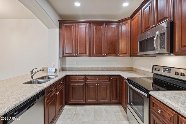 kitchen with light stone countertops, stainless steel appliances, a sink, and recessed lighting