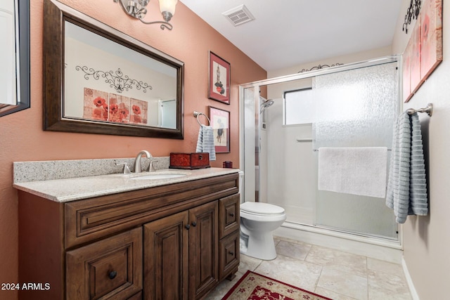 bathroom featuring vanity, a shower with shower door, and toilet