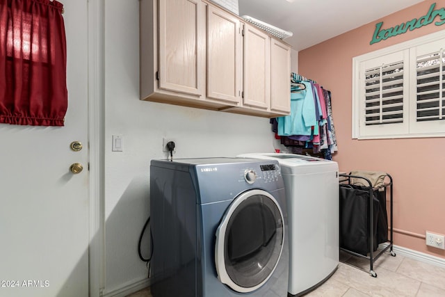 laundry area with washer and clothes dryer, light tile patterned floors, and cabinets