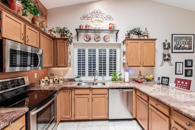 kitchen featuring sink, vaulted ceiling, light tile patterned flooring, light stone counters, and stainless steel appliances