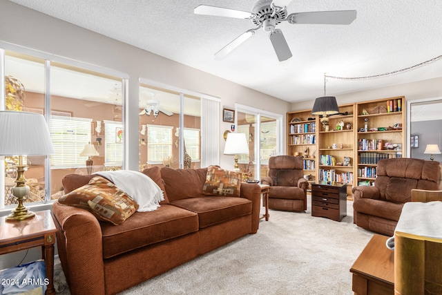 living room featuring ceiling fan, light colored carpet, and a textured ceiling