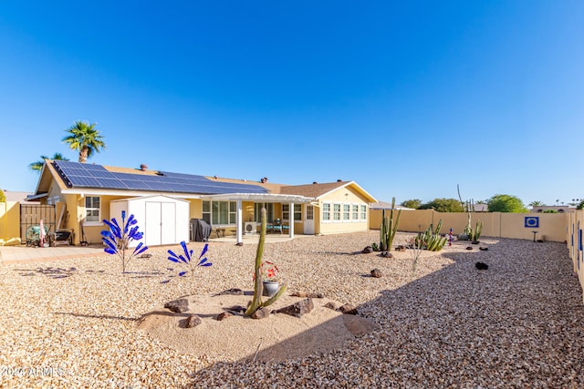 rear view of property with solar panels, a storage unit, and a patio area