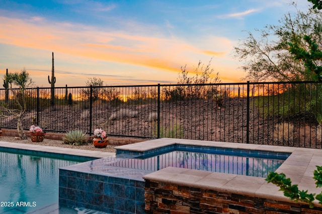 pool at dusk featuring a fenced backyard and a fenced in pool