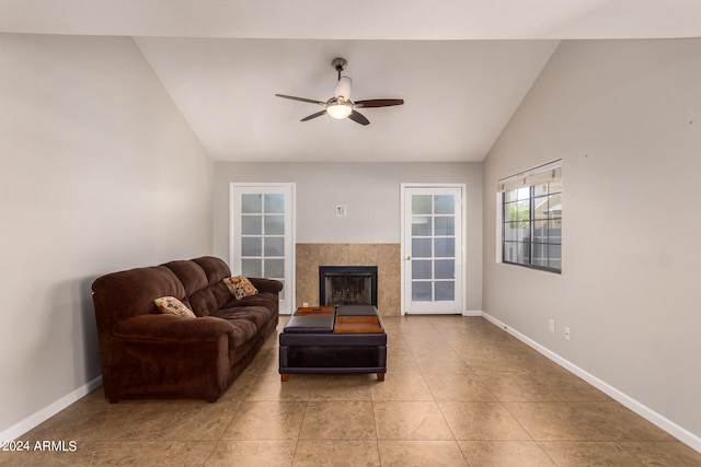 interior space featuring ceiling fan, a tiled fireplace, vaulted ceiling, and light tile floors