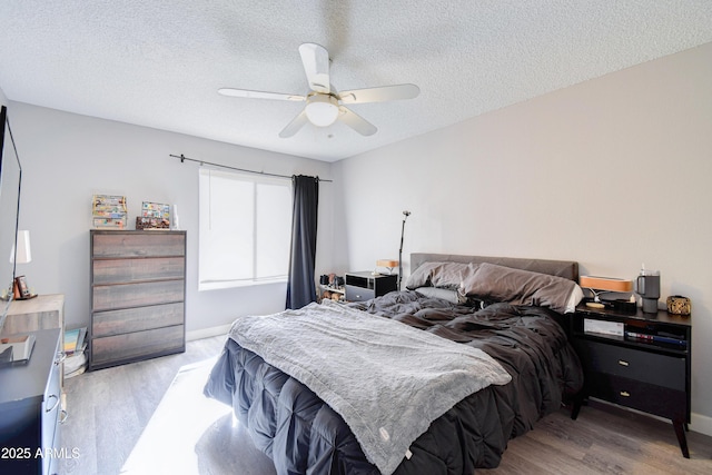 bedroom featuring ceiling fan, a textured ceiling, and light hardwood / wood-style floors