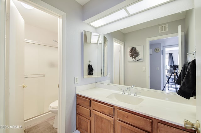 bathroom with vanity, toilet, and a shower with door