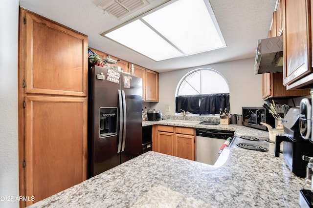 kitchen with a skylight, appliances with stainless steel finishes, sink, and kitchen peninsula