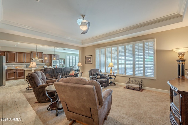 living room featuring a tray ceiling, ceiling fan, and crown molding