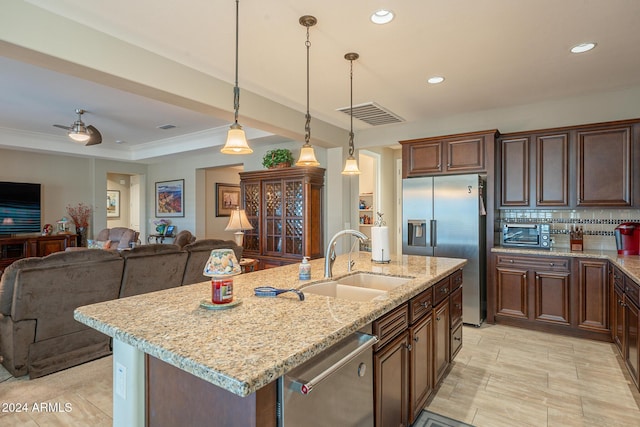 kitchen with appliances with stainless steel finishes, backsplash, sink, pendant lighting, and an island with sink