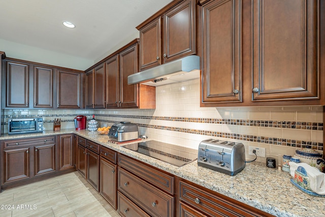 kitchen with light stone countertops, tasteful backsplash, and black electric cooktop