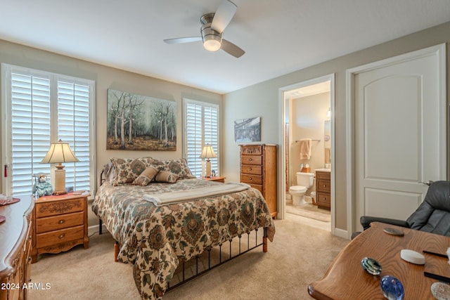 carpeted bedroom with ensuite bath and ceiling fan