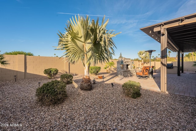 view of yard with an outdoor stone fireplace and a patio area