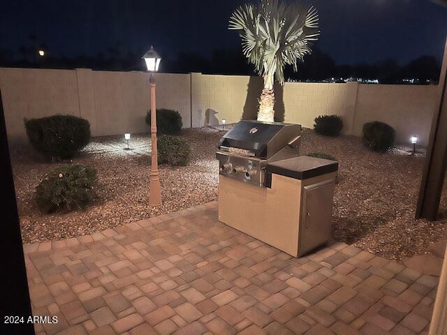 patio at night with area for grilling and an outdoor kitchen