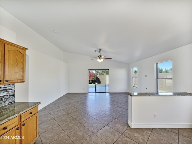 unfurnished living room featuring ceiling fan, a healthy amount of sunlight, lofted ceiling, and light tile patterned floors