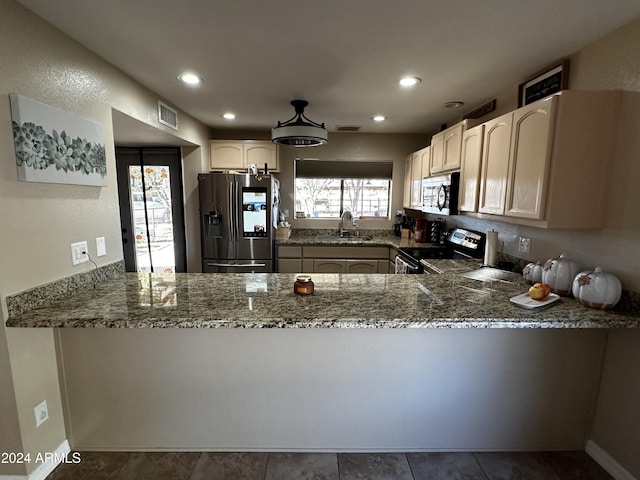 kitchen featuring kitchen peninsula, appliances with stainless steel finishes, a healthy amount of sunlight, sink, and dark stone countertops