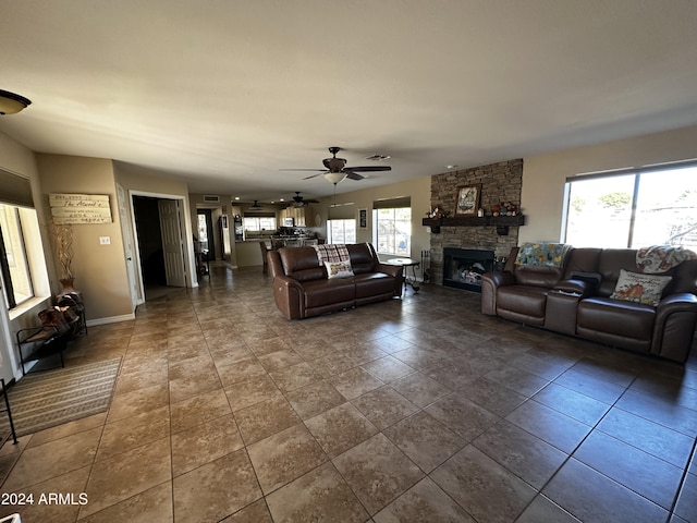 living room with a stone fireplace and ceiling fan