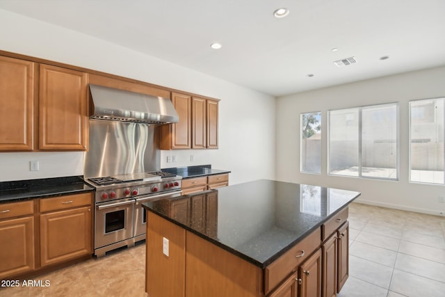 5557 W Mine Trl, Phoenix, AZ 85083 - kitchen with range with two ovens, wall chimney exhaust hood, a center island, brown cabinetry, and dark stone countertops