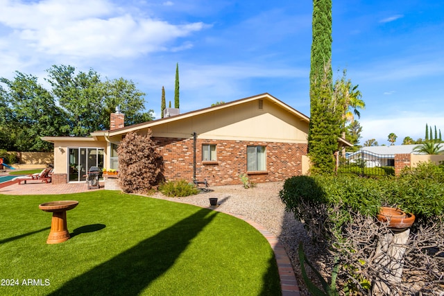 rear view of house featuring a yard and a patio