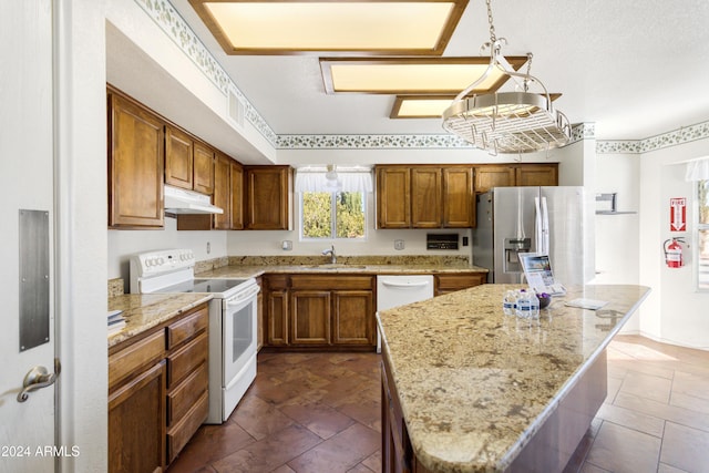 kitchen with a center island, decorative light fixtures, white appliances, and sink