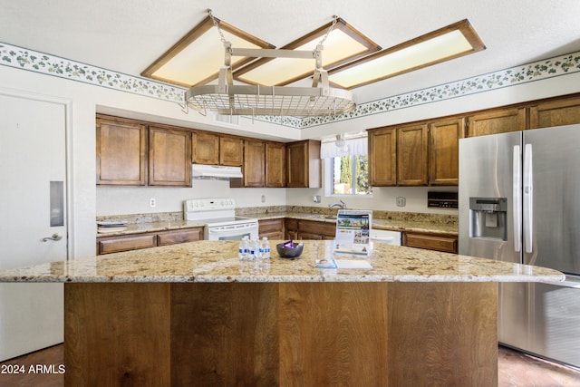 kitchen with a kitchen island, light stone counters, electric stove, and stainless steel refrigerator with ice dispenser