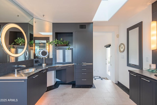 kitchen featuring a skylight, kitchen peninsula, and sink