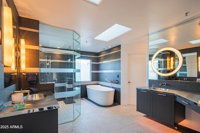 bathroom with vanity, shower with separate bathtub, and a skylight